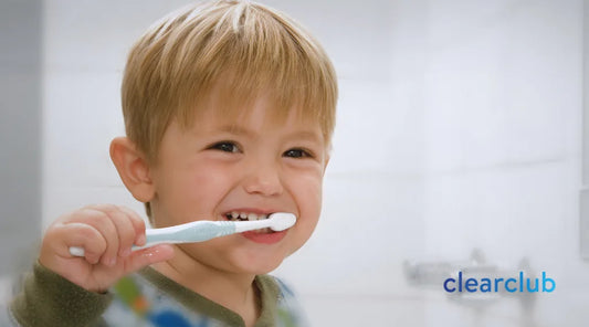 Toddler holding a toothbrush, emphasizing early oral hygiene before teeth whitening.