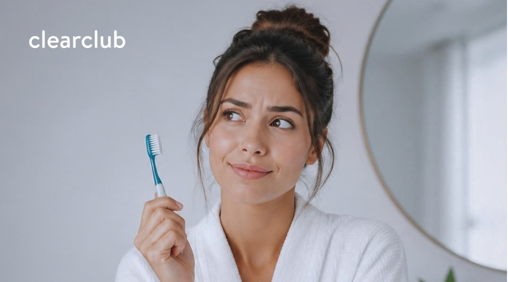 Woman thinking while holding a toothbrush, reflecting on common dental myths.