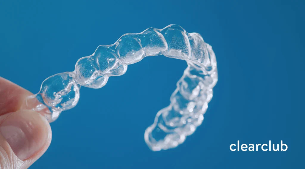Person holding a clear plastic retainer in good condition, the standard for preventing teeth misalignment.
