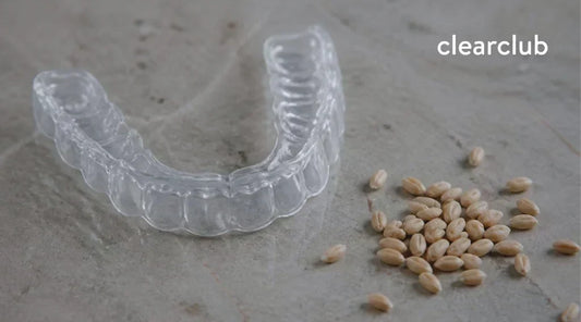 Clear dental night guard beside wheat grains representing gluten