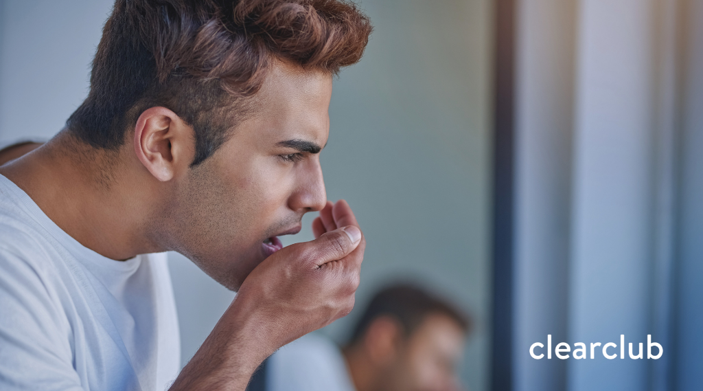 Man checking his breath by cupping his hand near his mouth, concerned expression, with ClearClub logo in the corner