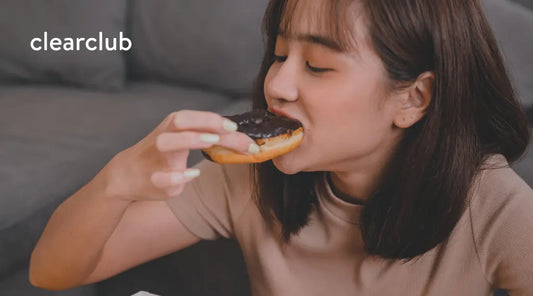 Woman eating a chocolate-topped donut.