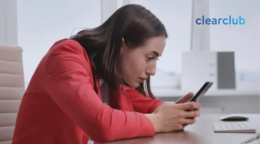 Woman looking down at her phone while sitting with a slouched posture.