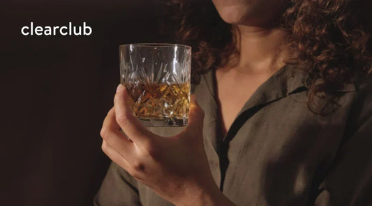 Woman holding a glass of alcohol while considering its possible effects on nighttime teeth grinding.