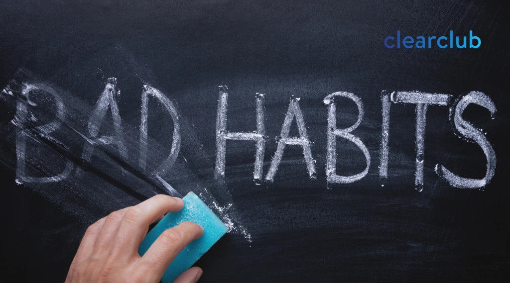 Person erasing the words ‘bad habits’ from a blackboard, symbolizing a desire to stop harmful dental habits.