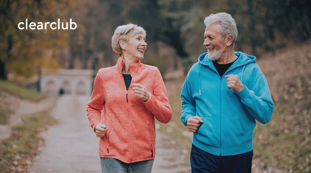 Two older adults jogging in the park, smiling and relaxed—showing how an active lifestyle can help ease stress and bruxism.