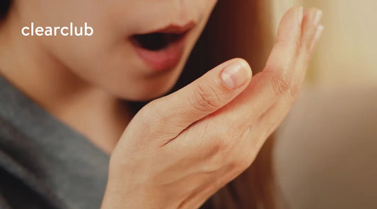 Woman checking her breath—possible bad odor from mouthguard