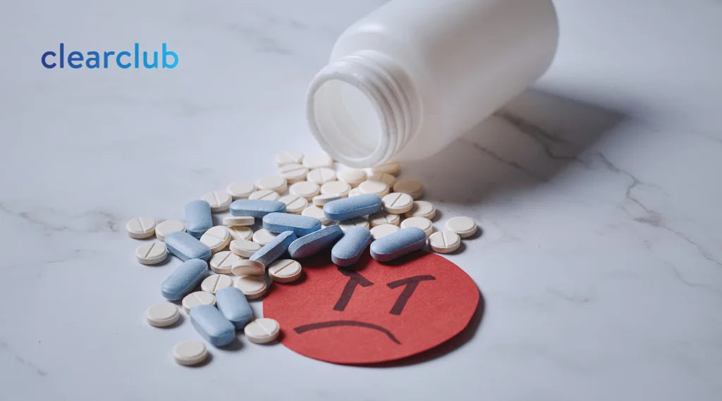 A bunch of pills on a marble countertop with a little angry face illustration, showing how antidepressants can contribute to teeth grinding.