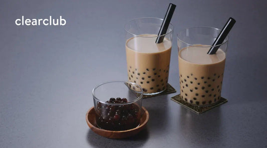 Two bubble tea drinks and a cup of tapioca pearls on a table, illustrating a beverage that can contribute to tooth staining.