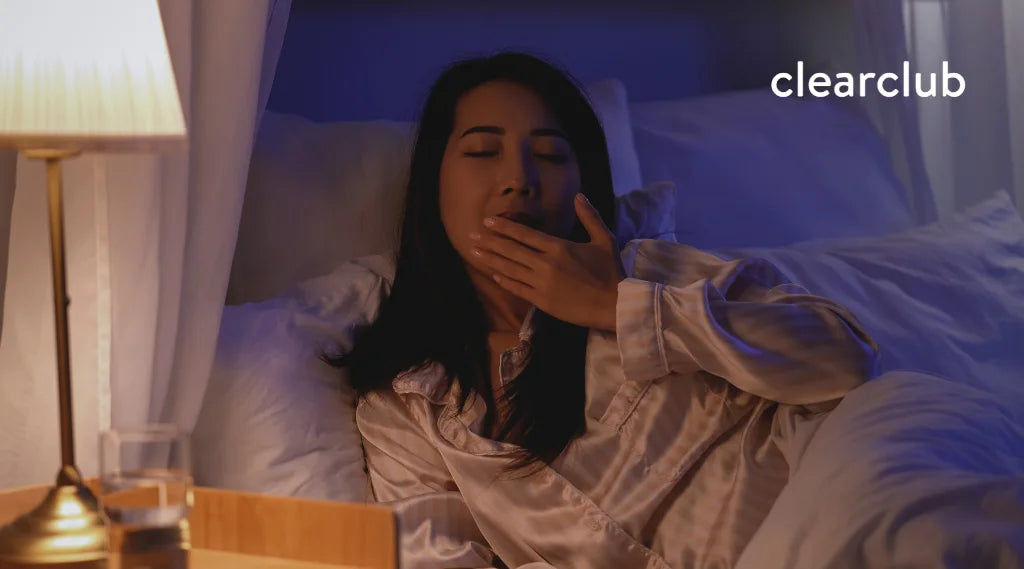 Woman yawning as she relaxes before bedtime — a simple way to ease stress and lower the risk of teeth grinding during sleep.