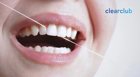 Person flossing between her front teeth as part of a retainer care routine 