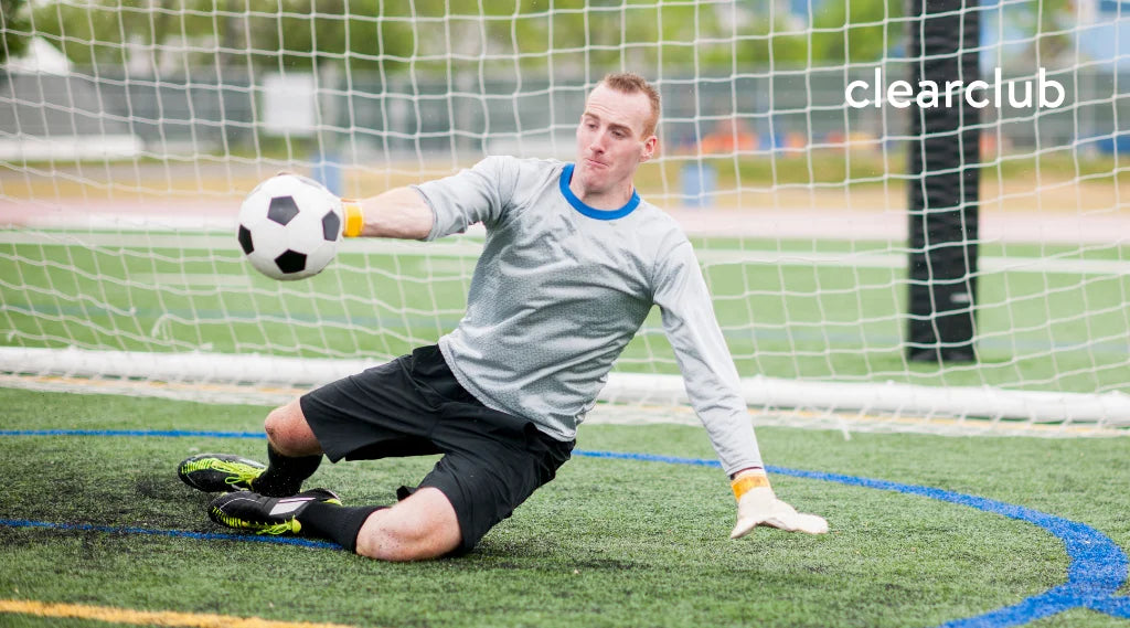 Goalkeeper diving to block a soccer ball near the goalpost, exposing the face to potential impact.