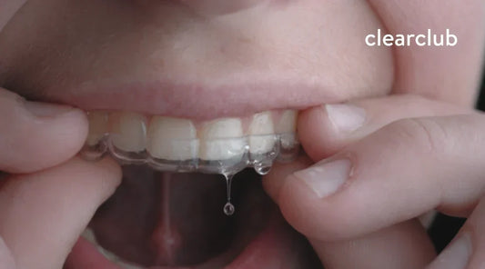 Woman removing a retainer from her mouth after experiencing excess saliva.
