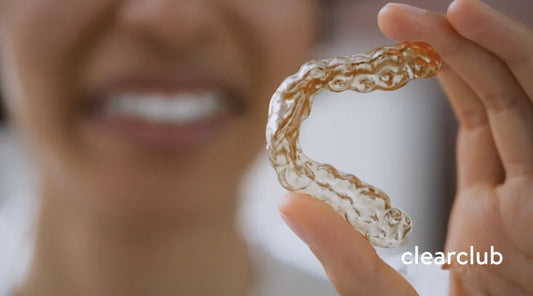 Yellowing mouthguard held by a woman reacting in disgust, indicating bacterial growth and mouthguard odor.