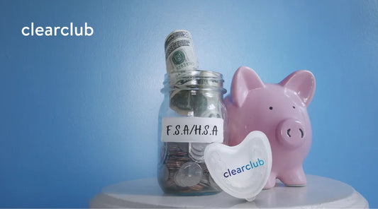 Jar labeled ‘FSA/HSA’ filled with coins and bills, next to a piggy bank and ClearClub night guard case, showing FSA/HSA savings for dental care.